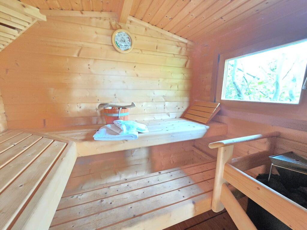Innenansicht einer Holzsauna mit Bänken und Fenster.