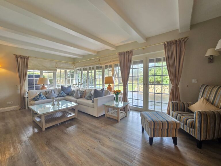 Geräumiges Wohnzimmer mit Glasfront, Sofas und Sesseln.