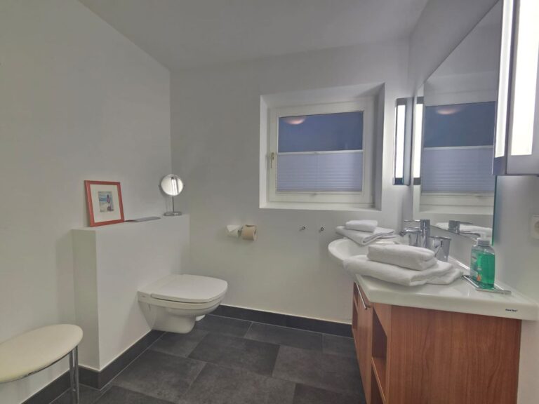 Modernes Badezimmer mit großem Spiegel, Handtüchern und Fenster.
