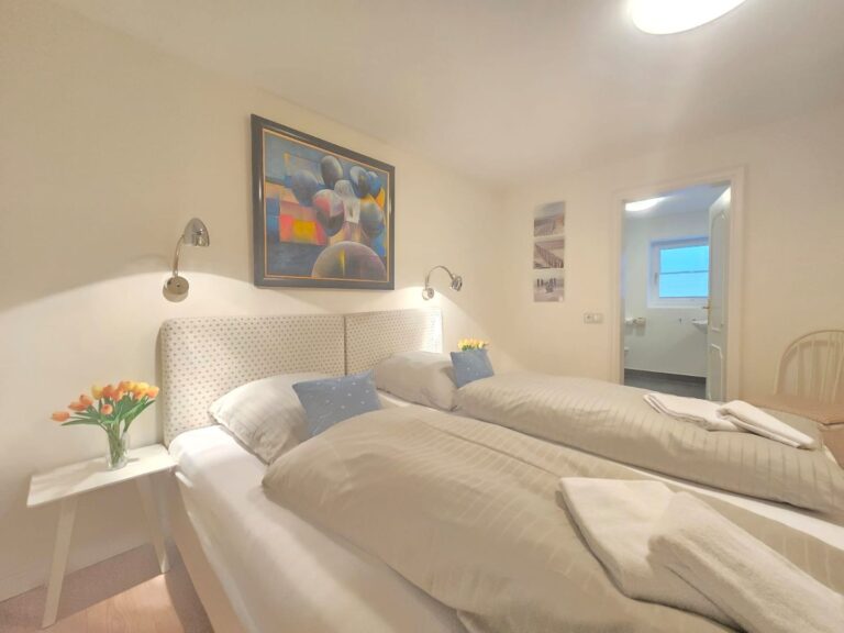 Schlafzimmer mit Doppelbett, künstlerischem Bild an der Wand und Nachttisch mit Blumen