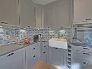 Moderne Küche mit grauen Schränken und blauer Fliesenrückwand.