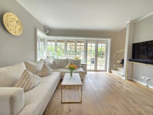Wohnzimmer mit weißem Sofa, Holzboden und großer Glasfront.